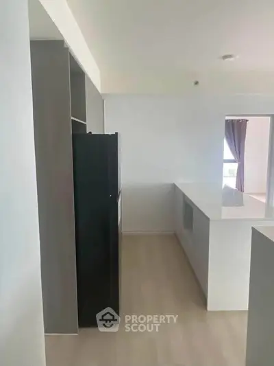 Modern kitchen with sleek design and open layout, featuring a black refrigerator and white countertops.