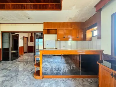 Spacious kitchen with marble flooring and wooden cabinetry in a modern apartment.
