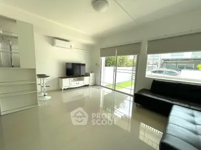 Spacious modern living room with sleek furniture and large windows offering natural light.
