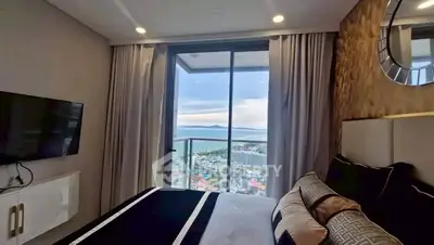 Luxurious bedroom with stunning ocean view from floor-to-ceiling windows in high-rise apartment.