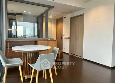 Modern dining area with stylish round table and chairs, featuring wooden flooring and large windows.
