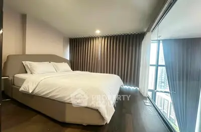 Spacious bedroom with modern decor and large windows offering city views.