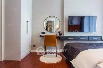 Modern bedroom with stylish decor, featuring a wall-mounted TV and elegant vanity area.