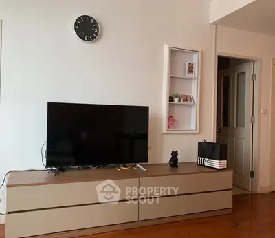 Modern living room with sleek TV stand and wall clock, showcasing minimalist decor.