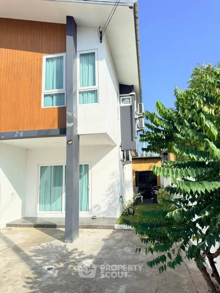 Modern two-story house with sleek design and spacious driveway, featuring large windows and a contemporary facade.
