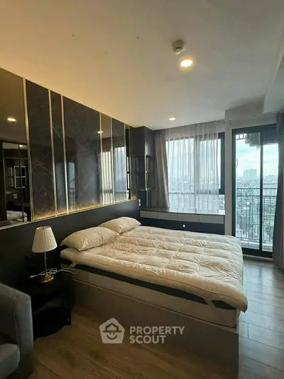 Luxurious bedroom with modern decor and city view balcony in high-rise apartment.