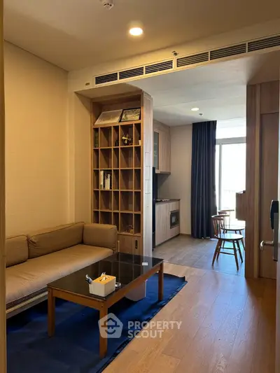 Modern living room with cozy sofa and open kitchen layout, featuring wooden flooring and stylish decor.