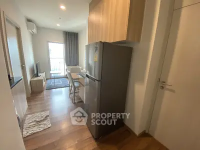 Modern apartment interior with open kitchen and cozy living area, featuring wooden flooring and natural light.