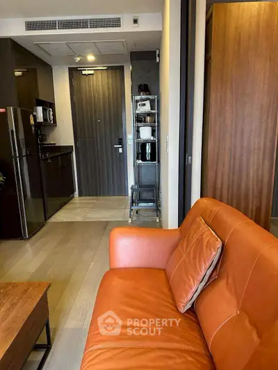 Modern apartment interior with stylish orange sofa and compact kitchen area.