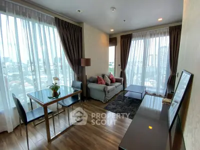 Modern living room with large windows and city view, featuring elegant decor and cozy seating area.