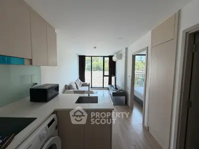 Modern open-plan living room with kitchen and balcony view in a stylish apartment.
