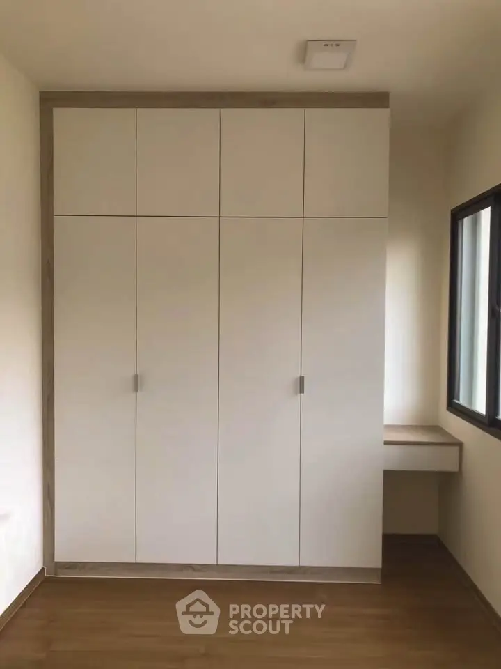 Modern minimalist bedroom with built-in wardrobe and natural light.