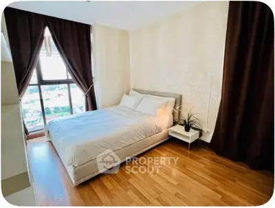 Cozy bedroom with large window and elegant decor, featuring hardwood floors and stylish curtains.