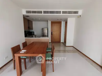Modern dining area with wooden table and chairs, adjacent to a sleek kitchen with stainless steel appliances.
