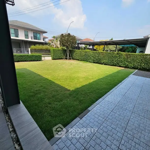 Spacious backyard with lush green lawn and modern paving in suburban home.