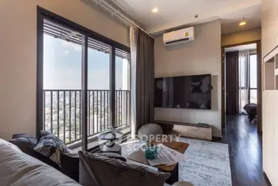 Modern living room with city view, large windows, and stylish decor in a high-rise apartment.