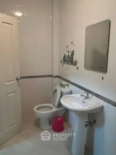 Cozy bathroom with modern fixtures and wall decor, featuring a sink, toilet, and mirror.