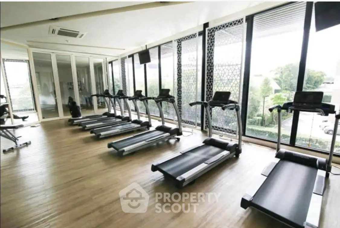 Modern gym with large windows and multiple treadmills in a luxury apartment complex.