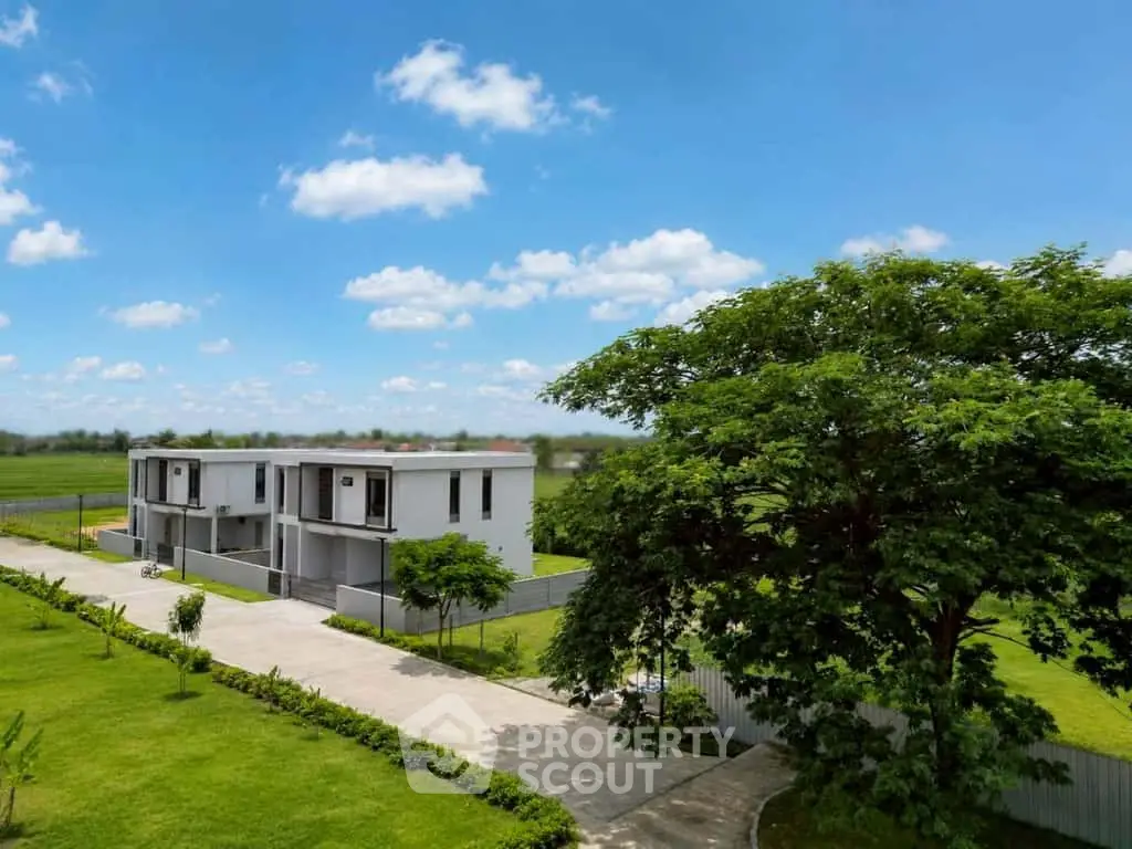 Modern duplex homes with lush greenery and clear blue skies, perfect for serene living.