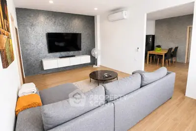 Modern living room with sleek design, large TV, and cozy gray sofa in open-plan layout.