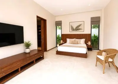 Spacious modern bedroom with elegant decor and large TV, perfect for relaxation.