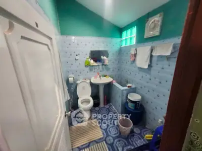 Cozy bathroom with blue patterned tiles and essential amenities, perfect for a compact living space.