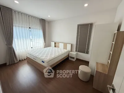 Spacious bedroom with modern furnishings and large window for natural light.