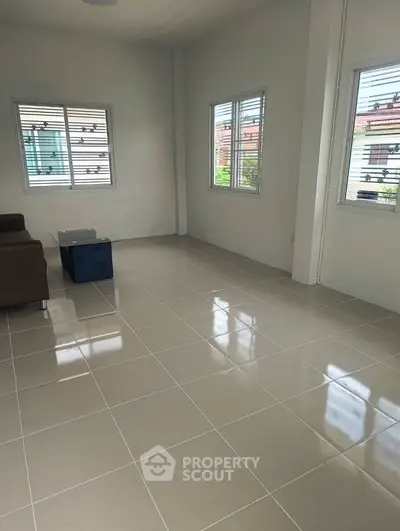 Spacious living room with tiled flooring and large windows offering natural light.