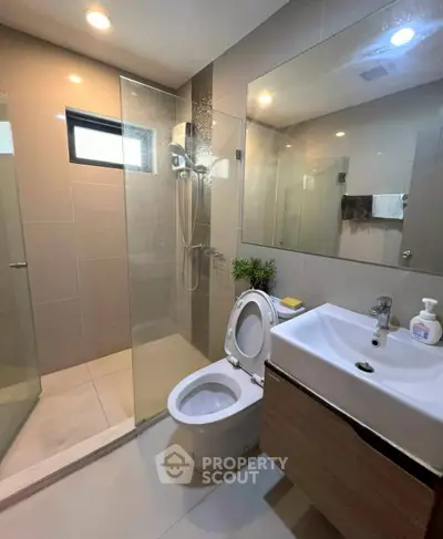 Modern bathroom with glass shower, sleek vanity, and natural light.