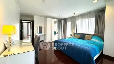 Spacious bedroom with modern decor and large windows for natural light.