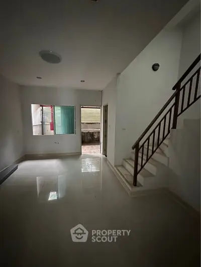 Spacious living room with staircase and large window, perfect for natural light.