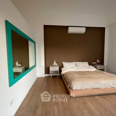 Modern bedroom with stylish decor and air conditioning, featuring a large mirror and wooden flooring.