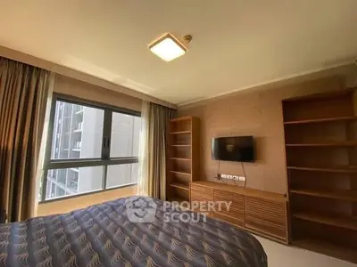 Spacious bedroom with modern decor and large window offering natural light.