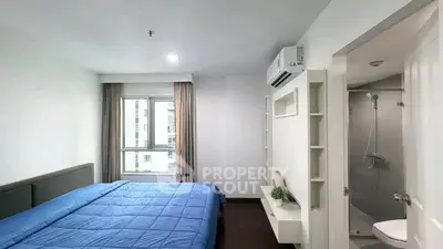 Modern bedroom with ensuite bathroom and large window in a stylish apartment.