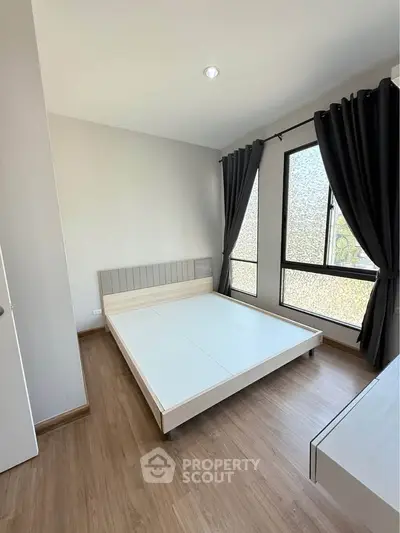 Modern minimalist bedroom with large windows and wooden flooring