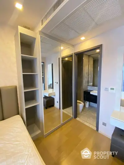 Modern bedroom with mirrored wardrobe and ensuite bathroom in luxury apartment