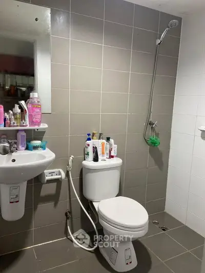 Modern bathroom with shower, toilet, and sink featuring tiled walls and floor.