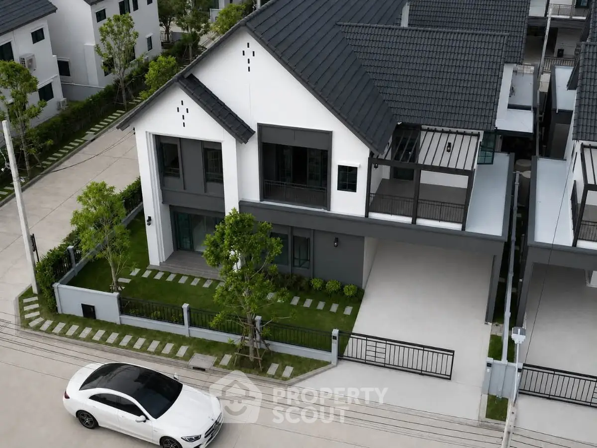 Modern two-story house with sleek design and spacious driveway in a suburban neighborhood.