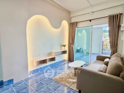 Stylish living room with modern lighting and cozy seating area, featuring sliding glass doors to balcony.