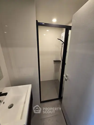 Modern bathroom with sleek shower enclosure and stylish sink in contemporary apartment.