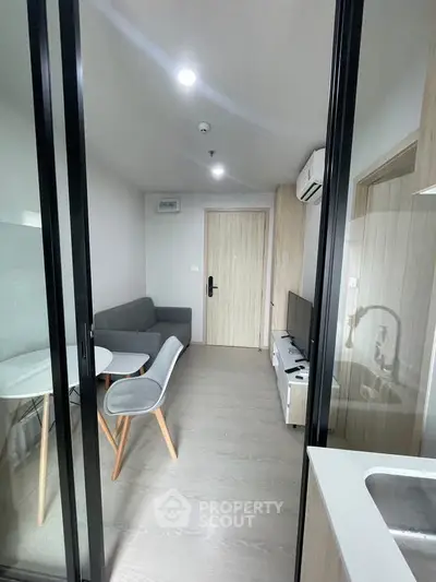 Modern living room with sleek furniture and glass partition in a stylish apartment.