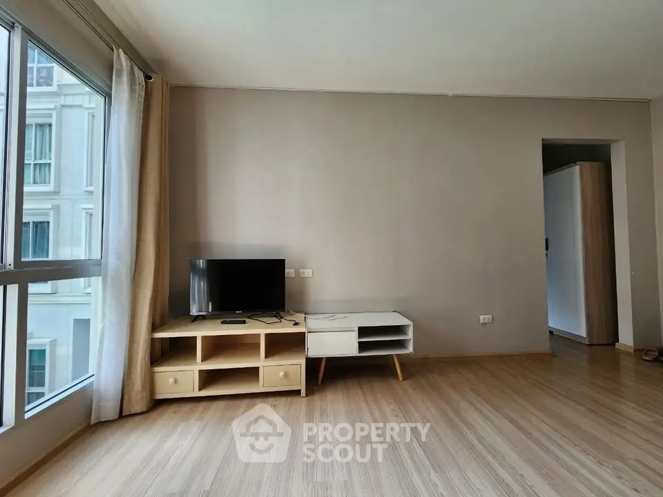 Spacious living room with large window and modern TV stand in a bright apartment.