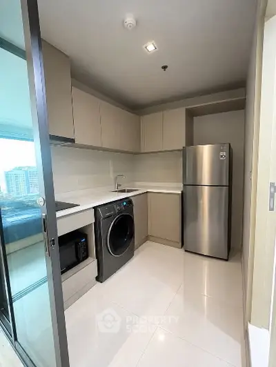 Modern kitchen with sleek appliances and ample storage in a contemporary apartment.