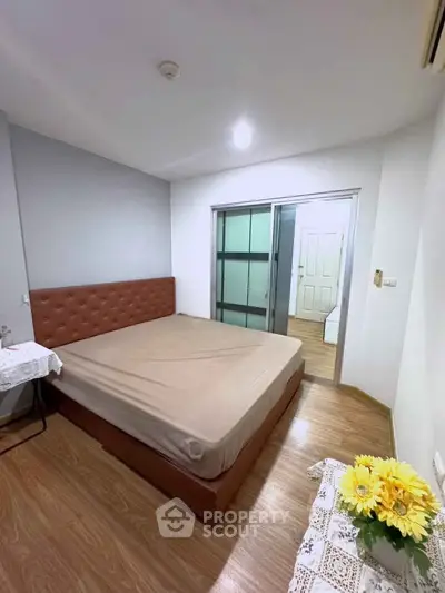 Cozy bedroom with wooden flooring and sliding glass doors, perfect for relaxation.