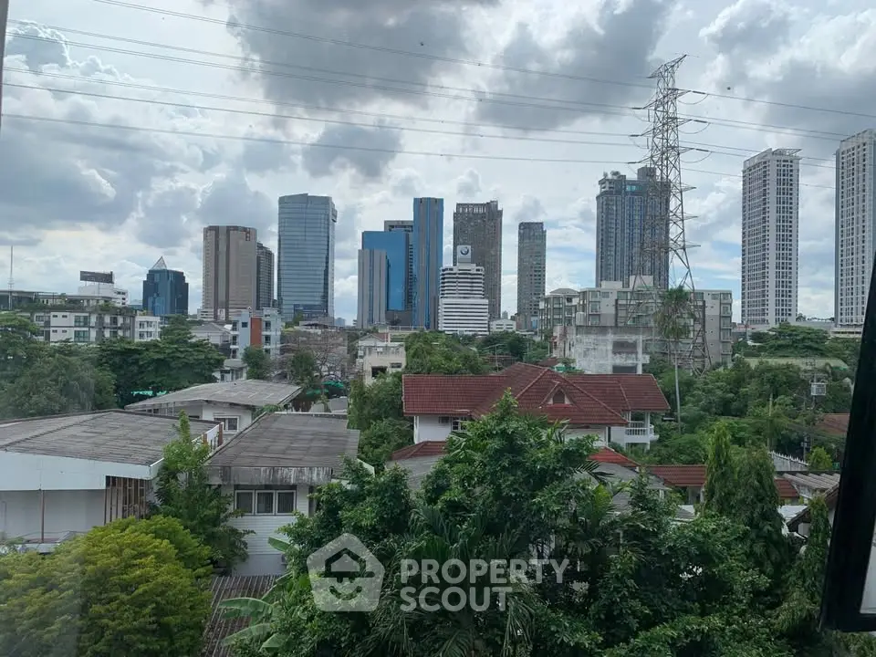 Stunning cityscape view with lush greenery and modern skyscrapers under a cloudy sky.