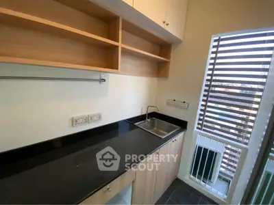Modern kitchen with sleek black countertop and open shelving, featuring a compact sink and city view.