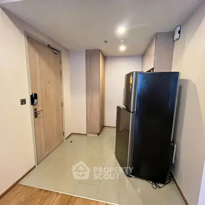 Modern apartment entryway with sleek refrigerator and wooden flooring