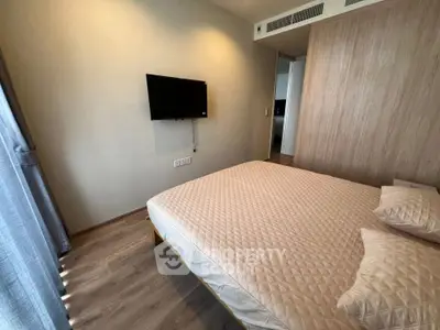 Modern bedroom with wall-mounted TV and stylish bedding