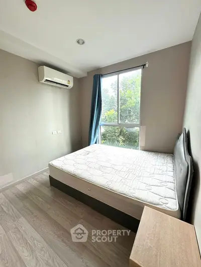 Bright bedroom with large window and air conditioning unit, featuring a comfortable bed and modern decor.