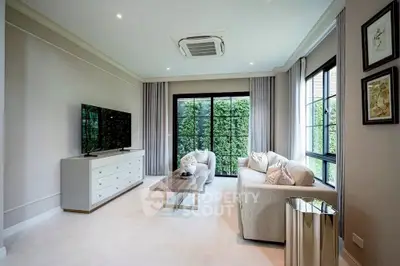 Elegant living room with modern furniture and large windows overlooking lush greenery.